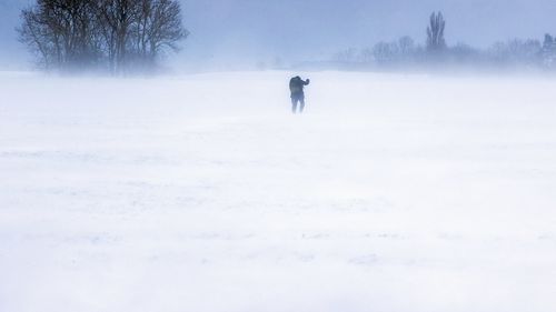 A man walks across a snow-covered field on the island of Ruegen, Germany, Sunday, Feb. 7, 2021. Strong winds are causing snow drifts in the north of the island. The German Weather Service (DWD) expects snowstorms and permafrost for northern Germany this weekend. (Jens Buettner/dpa via AP)