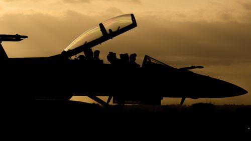 A silhouetted RAAF F/A-18F Super Hornet