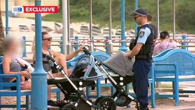 A young mother breastfeeding is spoken to by police.