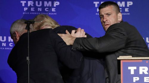 Trump is rushed off stage by Secret Service agents. (AAP)