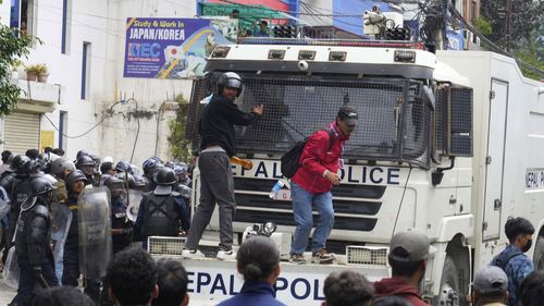 Os manifestantes bloqueiam um veículo blindado durante confrontos do lado de fora do prédio do Parlamento em Katmandu, Nepal.