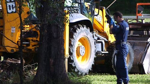 Police take photographs as an excavator works to dig up the backyard. (9NEWS)