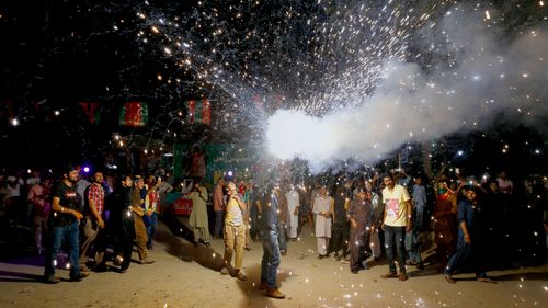 A supporter of Imran Khan releases fireworks to celebrate projected unofficial results of the Pakistan election. (AAP)
