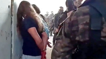 In this image taken from video provided by the Hostage Families Forum, Israeli female soldiers from the Nahal Oz military base are placed against the wall and shackled by members of Hamas after they were taken captive on October 7.