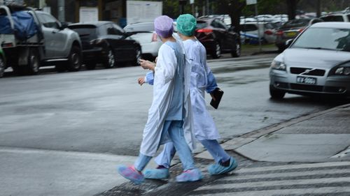 Health workers cross the road near Concord Repatriation General Hospital in Concord, NSW.