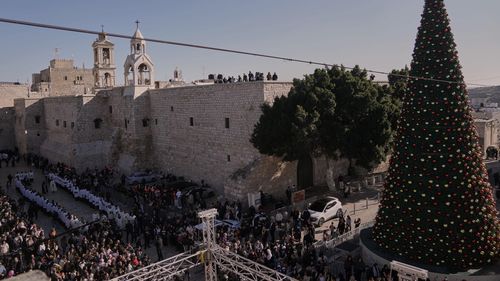 Clero católico caminha em procissão ao lado da Igreja da Natividade