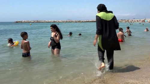 Nissrine Samali, 20, gets into the sea wearing a burkini, a wetsuit-like garment that also covers the head, in Marseille, southern France.