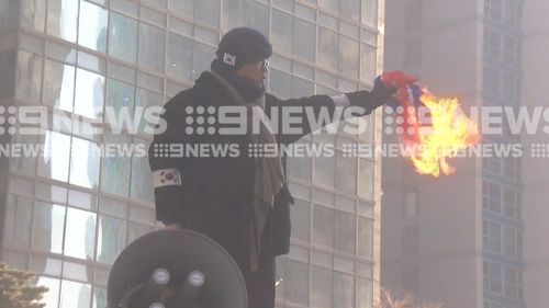 A North Korean flag is burnt in the protests. (9NEWS)