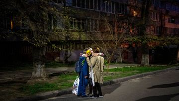 Three women embrace in a street in Kyiv after a Russian attack