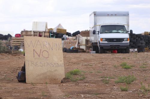This photo shows a "no trespassing" sign outside the location where people camped near Amalia, N.M. Three women believed to be the mothers of 11 children found hungry and living in a filthy makeshift compound in rural northern New Mexico have been arrested, following the weekend arrests of two men, authorities said Monday, Aug. 6. (Jesse Moya/Santa Fe New Mexican via AP)