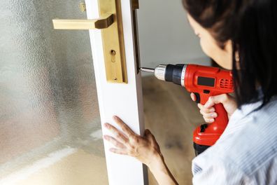 Woman using electronic drill install door