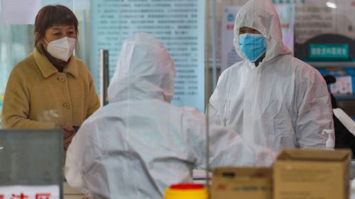 Medical workers in protective gear talk with a woman suspected of being ill with a coronavirus at a community health station in Wuhan in central China's Hubei Province.