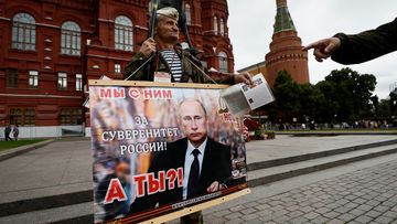 A man holds a placard in support of Russian President Vladimir Putin as a tower of the Kremlin is seen in the background, in Moscow, Russia, June 24, 2023.  