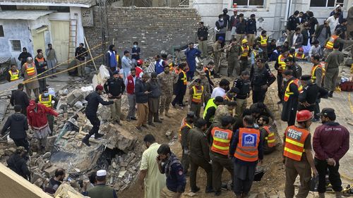 Security officials and rescue workers search bodies at the site of suicide bombing, in Peshawar, Pakistan.