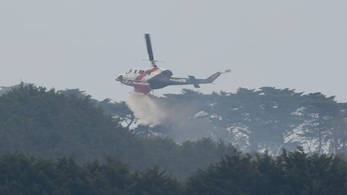 A helicopter drops water on the out-of-control blaze in Somerville. (AAP)