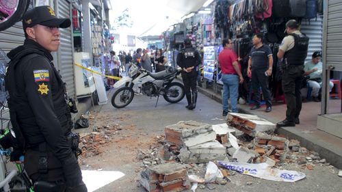 Police stand by debris fallen from a building at a commercial area after an earthquake shook Machala, Ecuador, Saturday, March 18, 2023. 