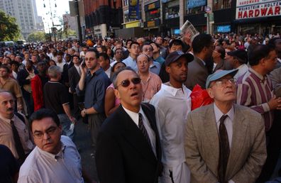 People watch World Trade Center burn on September 11, 2001 after two hijacked airplanes slammed into the twin towers in New York City.