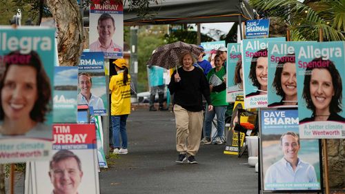 Locals run the gauntlet of election posters at Sydney's Wentworth headquarters.
