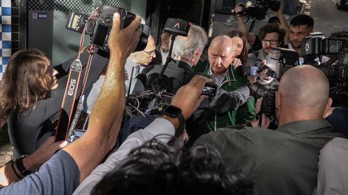 Alan Jones is surrounded by a scrum of journalists outside a Sydney police station.