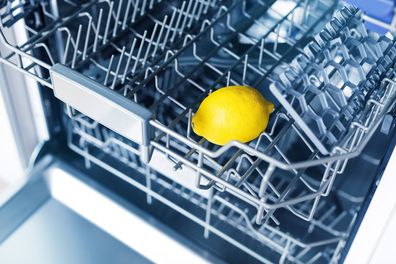 Empty dishwasher with fresh yellow lemon on shelf, aroma freshness care concept, clean equipment,  home appliance dishwashing machine in kitchen interior, no people