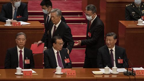 Председатель КНР Си Цзиньпин и премьер-министр Ли Кэцян (слева) и член Политбюро Ван Ян разговаривают с бывшим президентом Ху Цзиньтао (в центре), когда ему помогают уйти в начале заключительного заседания 20-го Всекитайского конгресса Коммунистической партии.  Китай.