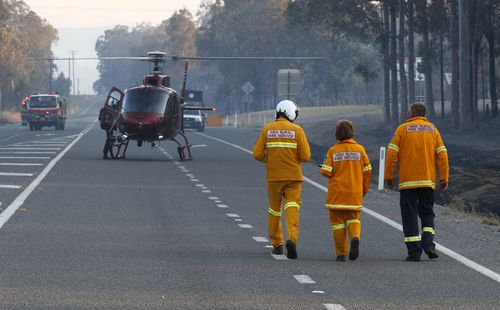 ncident Controller Neil Mutton (right) heads to a helicopter to get an aerial view of a bushfire. (AAP)