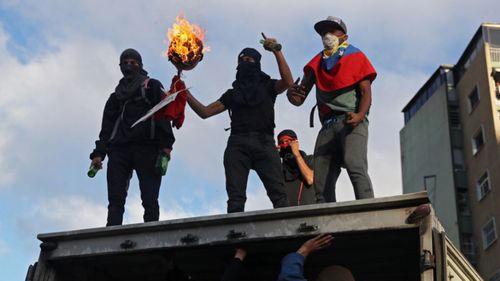 Protesters vandalise a lorry as thousands take to the streets during a demonstration against President Maduro in Caracas.
