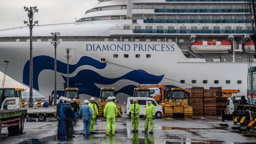 Workers gather on the dock next to the Diamond Princess cruise ship in Yokohama, Japan.
