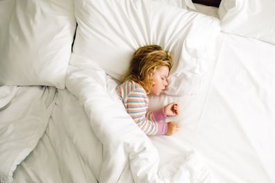 Cute little toddler girl sleeping in big bed of parents. Adorable baby child dreaming in hotel bed on family vacations or at home