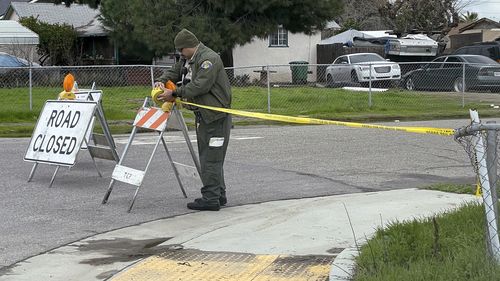 A Tulare County Sheriff's Deputy cordons off a road, Tuesday, Jan. 17, 2023 as detectives continues to investigate a shooting that left six people dead early Monday morning in Goshen California.