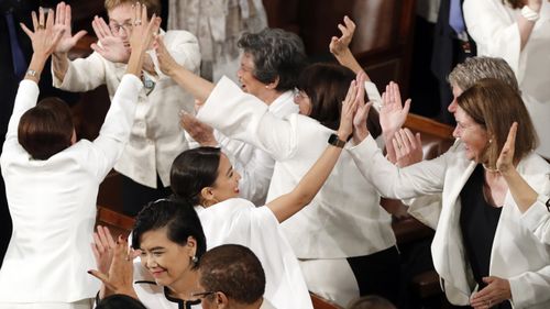 Democrats dressed in white respond during Mr Trump's speech.