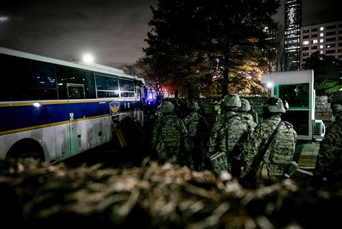 Soldiers wait to board a bus as they leave the National Assembly after lawmakers voted on a request to lift the state of emergency previously declared by South Korean President Yoon Suk Yeol in Seoul, South Korea, early Wednesday, Dec. 4, 2024. Yoon stunned voters , lawmakers and investors declared a state of emergency on Tuesday after he accused the opposition of trying to paralyze his administration amid a political rift that is set to deepen significantly. Photographer: Woohae Cho/Bloomberg