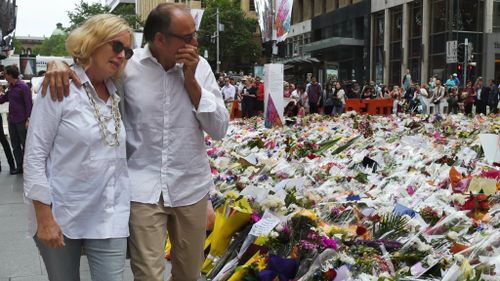 Grieving relatives of Tori Johnson and Katrina Dawson visit the floral tribute to the two Sydney siege victims in Martin Place. (AAP)