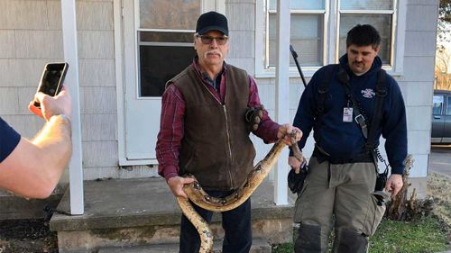 Butler County deputy fire chief Melvin Linot takes the boa constrictor from the house.