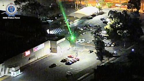 A man with a laser beam shines the powerful light towards a NSW Police chopper.