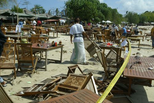 Um homem começa a limpar a praia de Jimbaran após os atentados de 2005 em Bali.