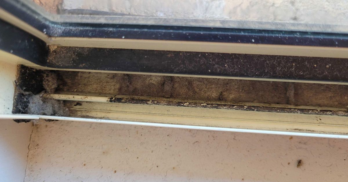 A close-up of a dirty window track before being professionally cleaned.
