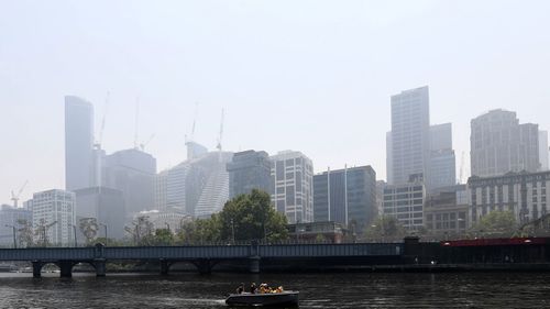 A boat motors down the Yarra River in Melbourne, Friday, January 3, 2020. A smoke haze has drifted over the city from the bushfires in East Gippsland