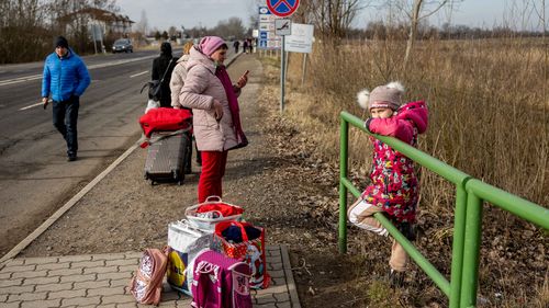 People wait with their belongings at the Astely-Beregsurany border crossing  in Beregsurany, Hungary. 