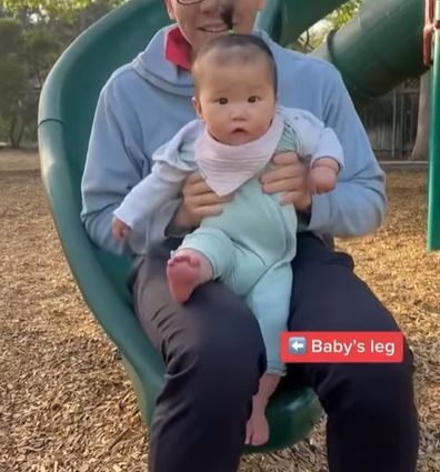 Dad going down slide with baby. 