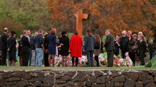 Families and friends gather around the memorial at Port Arthur for a minute's silence at a service in memory of the 35 people killed, on the first anniversary in 1997. (AAP)