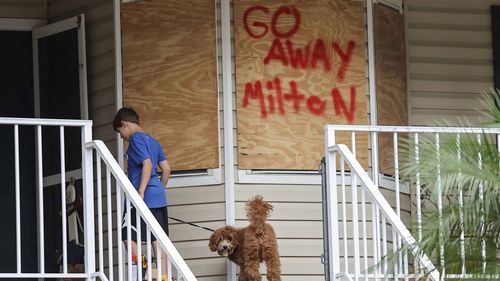 Noah Whipple e il suo cane Cookie salgono le scale verso casa loro mentre la loro famiglia si prepara per l'uragano Milton lunedì 7 ottobre 2024 a Port Richey, in Florida.