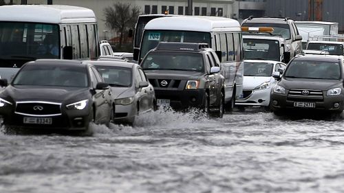 People drive their cars through a flooded street in Dubai. (AAP)