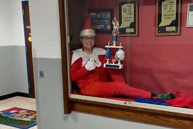 Beth Hoeing sitting in the school's trophy cabinet dressed as an elf.