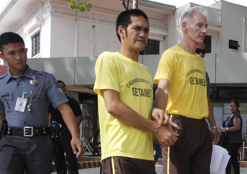 Peter Gerald Scully of Australia, right, walks in handcuffs with an unidentified detainee as they arrive at Cagayan de Oro city hall in southern Philippines on Tuesday, June 16, 2015. (AAP)