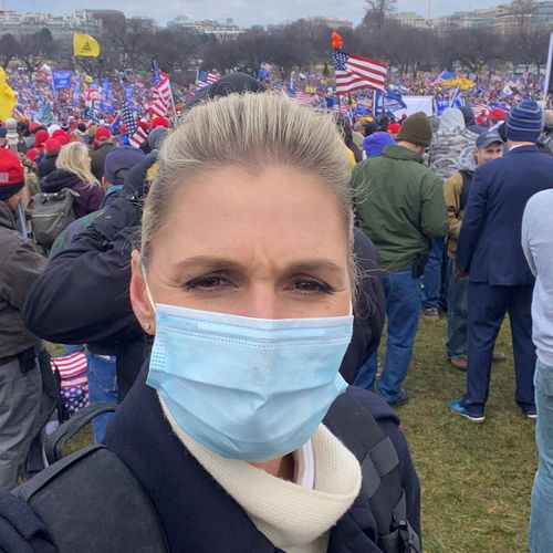 Amelia in a mask in front of a Trump rally.