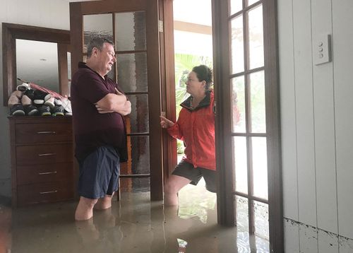 Amelia Rankin checks on her neighbour Adam Hanson in Hermit Park, Townsville, Monday, February 4, 2019. The line on the wall at the right shows the water level reached overnight. 