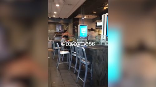 The video shows a shoeless woman wearing figure-hugging shorts and a crop top seated with her meal, yelling across the restaurant at someone off camera. Picture: Facebook/Marie Dayag