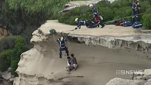 Rescue crews work to save the pair stuck on the ledge. (9NEWS)
