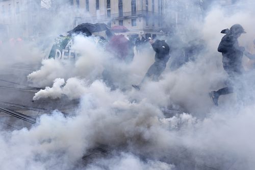 Youths run though tear gas during a protest in Nantes, western France, on Thursday, April 6, 2023. 